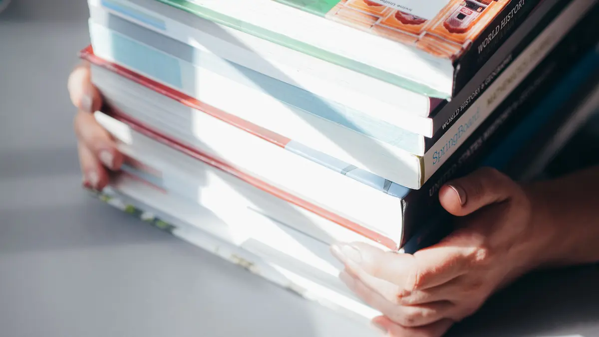 Pile de livres tenus à deux mains, illustration des guides santé